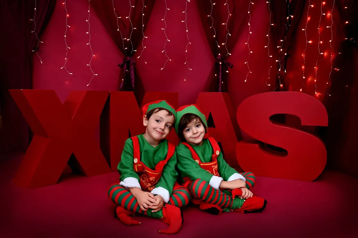 Dos hermanos sentados delante de las letras XMAS en la sesión de Navidad 2026