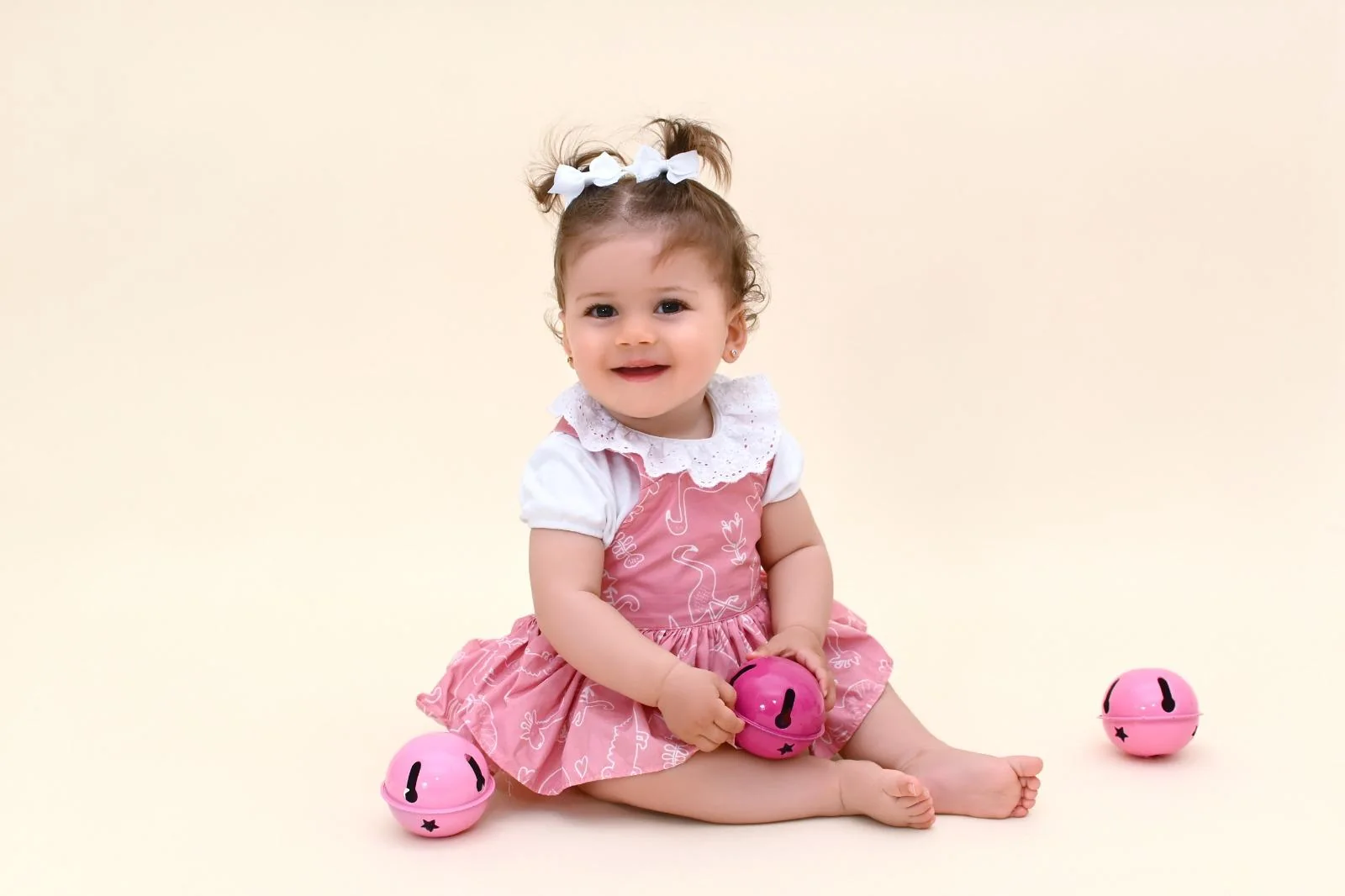 Niña de un año con vestido rosa sonriendo en el estudio antes de su Smash Cake