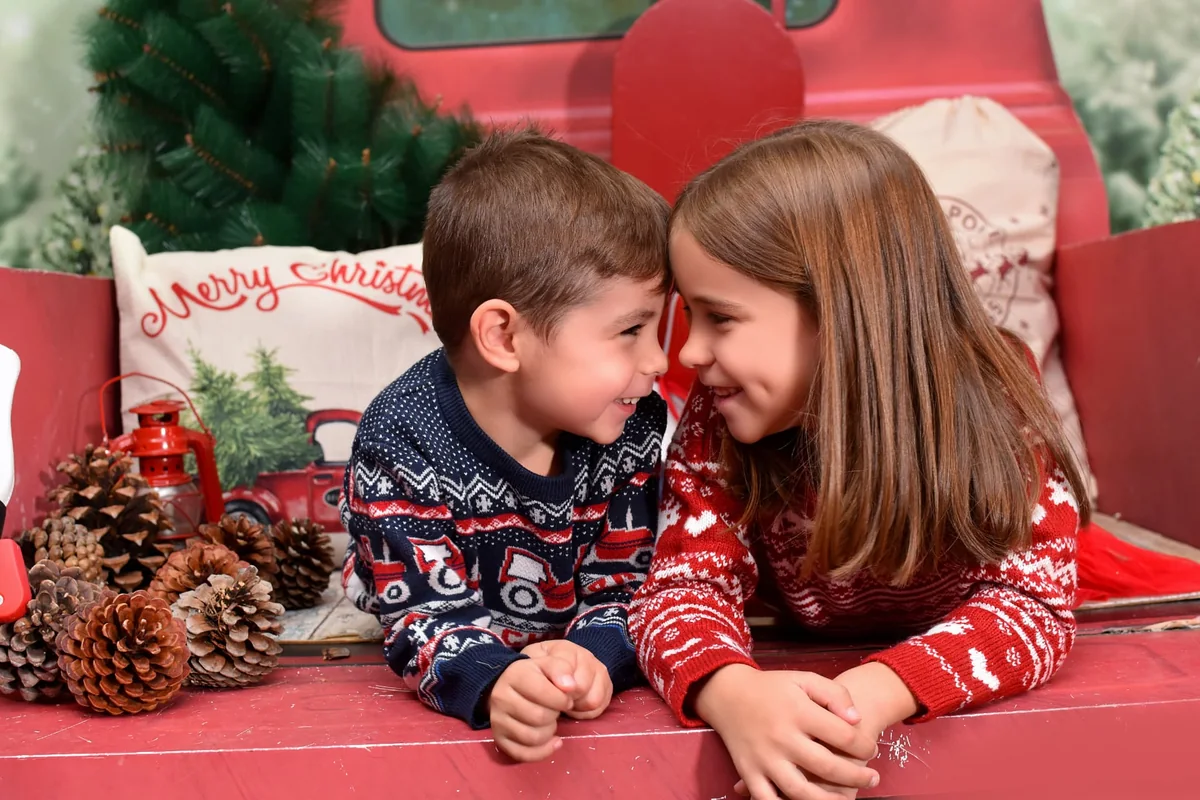 Dos hermanos sonríen juntos en una camioneta roja durante la campaña de Navidad 2021