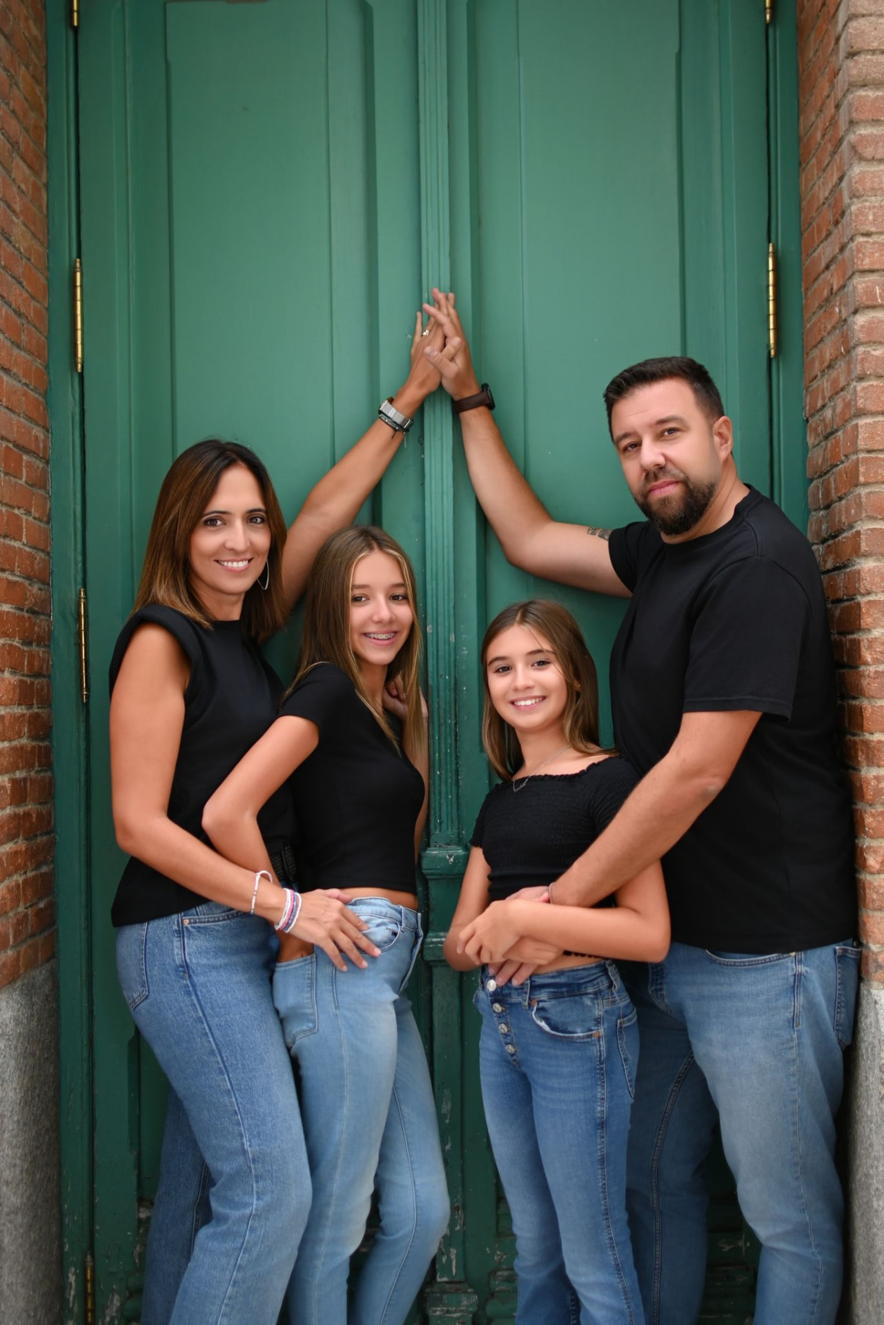 Familia sonriendo junto a una puerta verde, un retrato de confianza construida a lo largo de los años