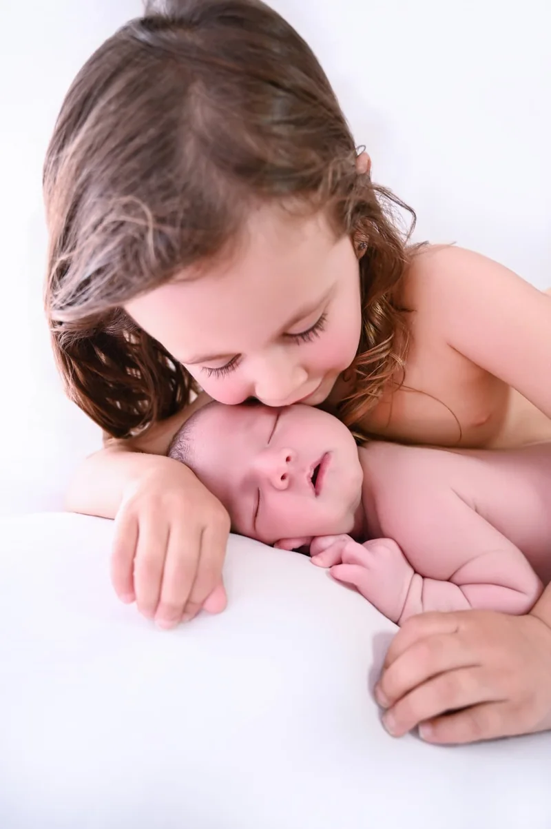 Hermana mayor junto a su hermano recién nacido durante una sesión newborn familiar en Fuenlabrada