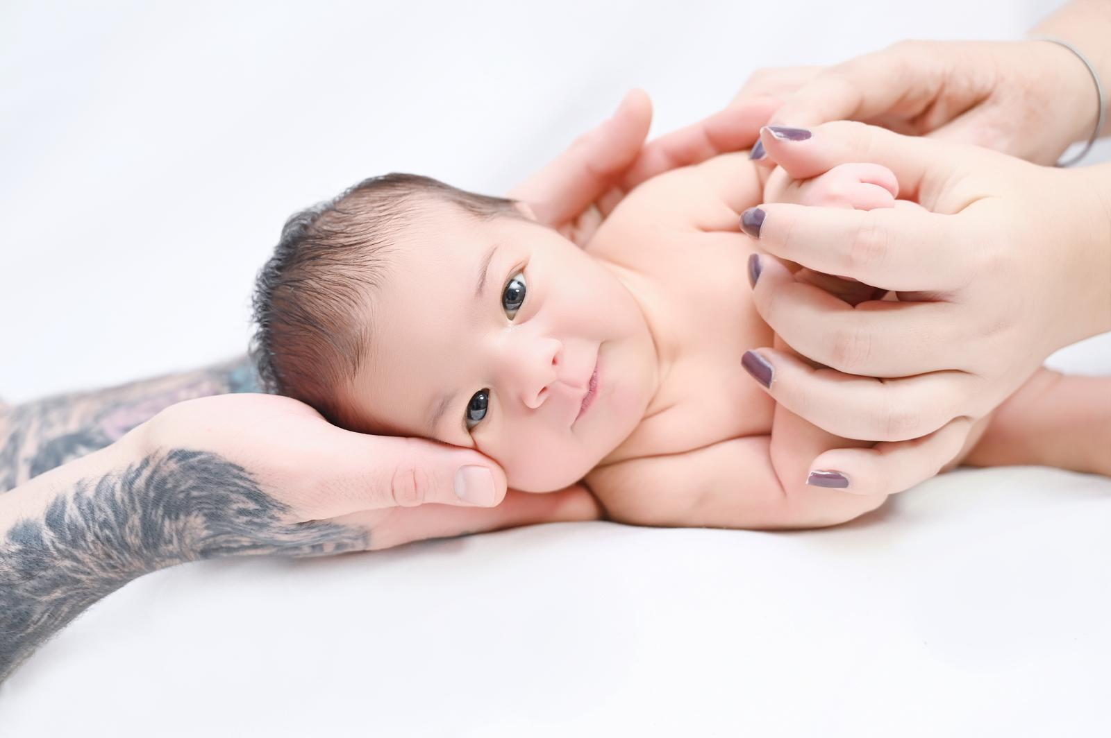 Bebé recién nacido descansando sobre las manos de sus padres