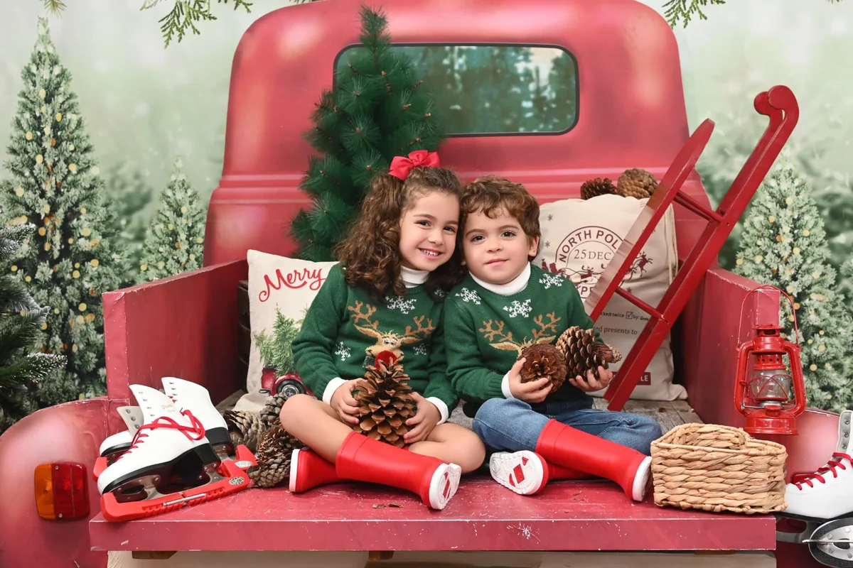 Dos niños con jerséis verdes sentados en una camioneta roja durante la campaña de Navidad 2021