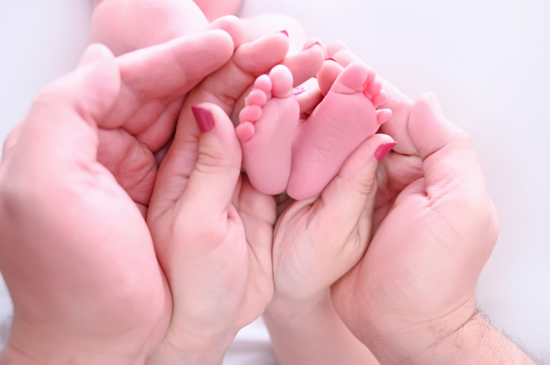 Macro de los pies de un bebé recién nacido sobre las manos de sus padres