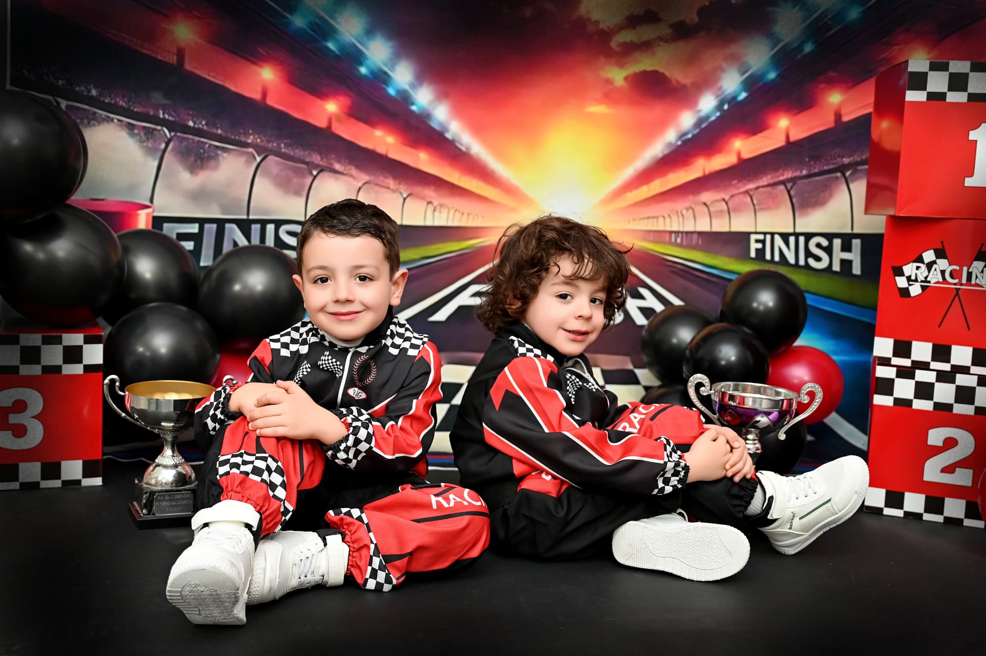 Dos niños con monos de carreras y trofeos en una sesión de fotos de cumpleaños infantil en Fuenlabrada