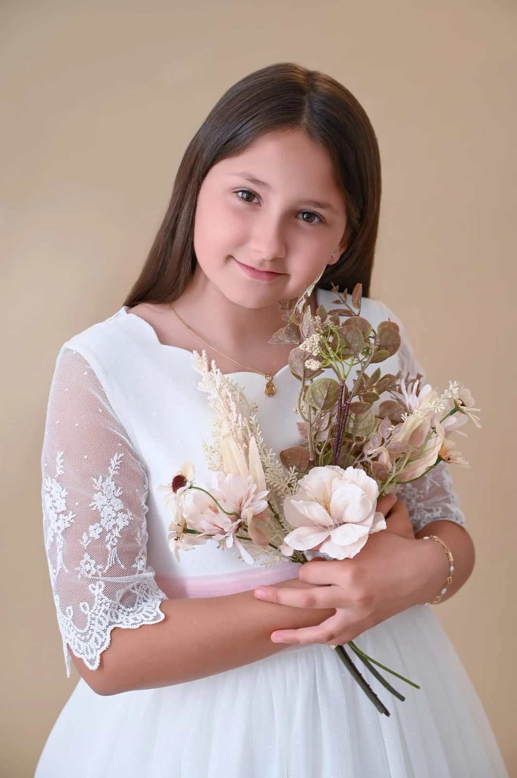 Retrato de niña de Comunión con vestido de encaje y ramo de flores en estudio