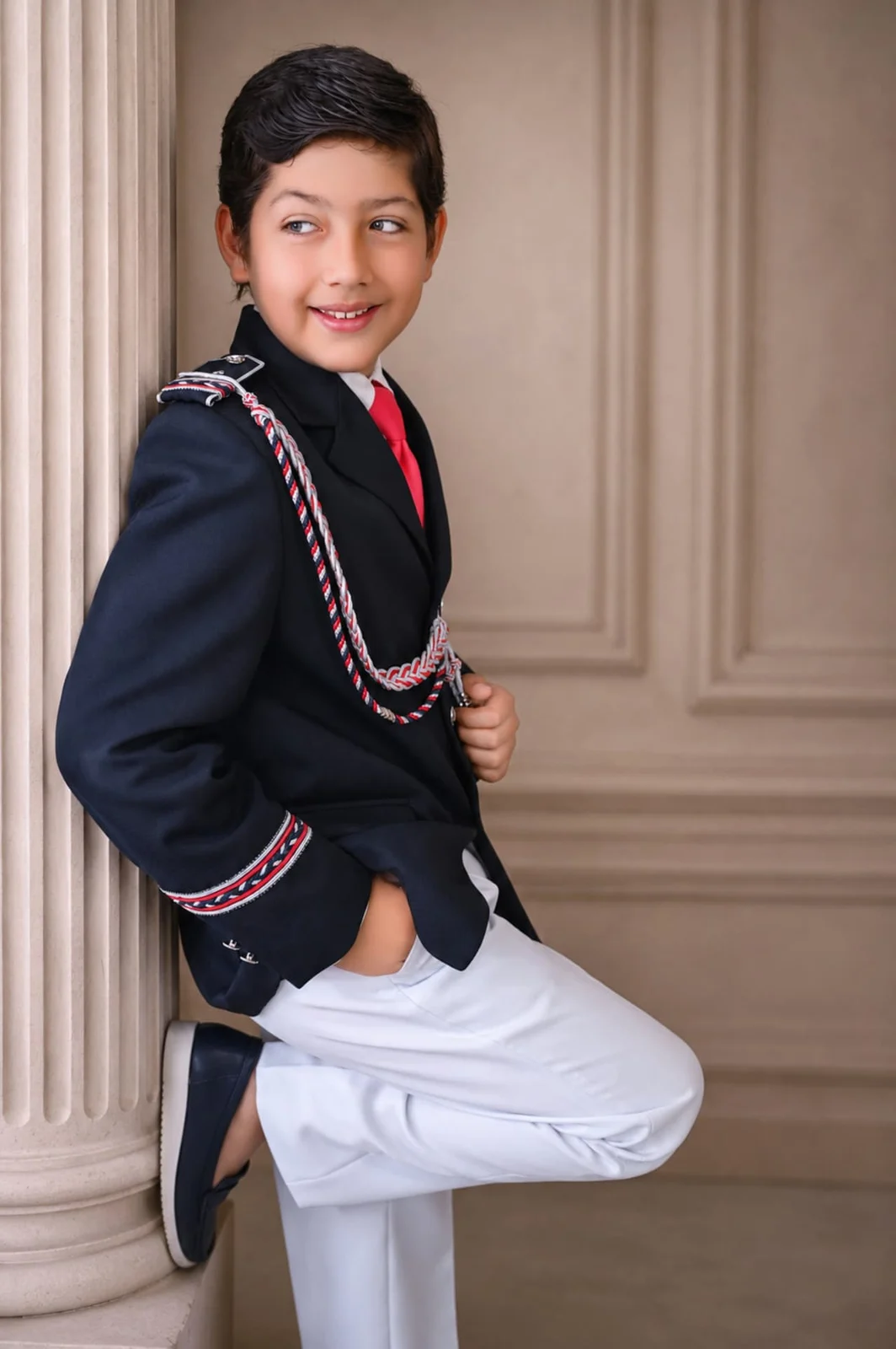 Fotografía de Comunión de niño con traje de almirante junto a una columna en estudio en Fuenlabrada