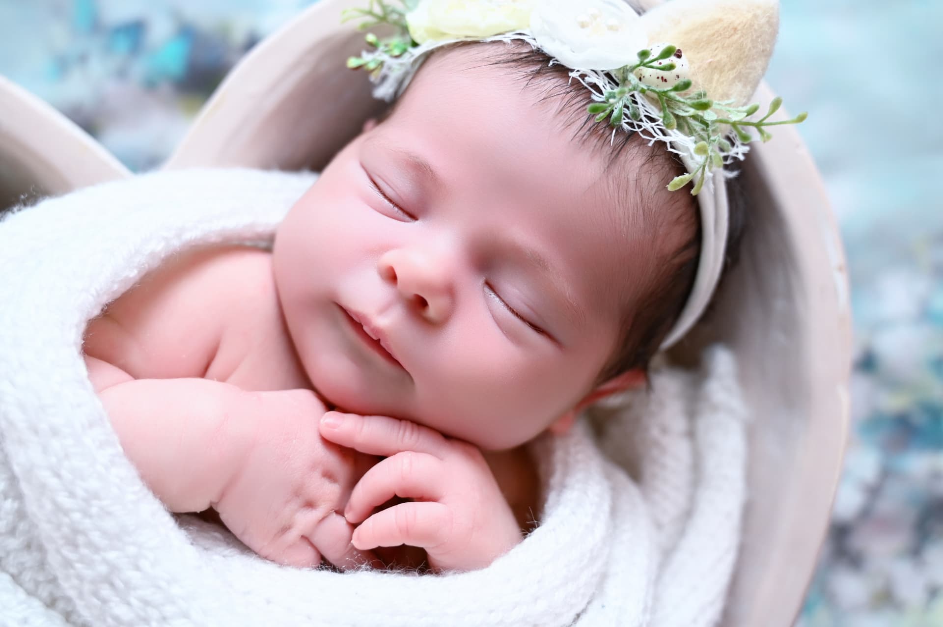 Bebé recién nacido dormido con corona de flores durante su sesión newborn