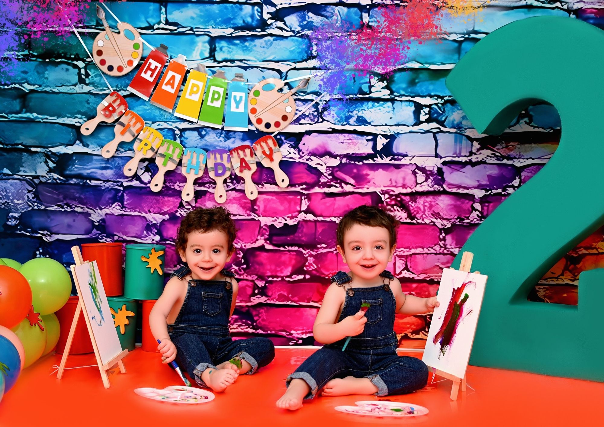 Dos niños pintando en un escenario lleno de color durante su sesión de cumpleaños
