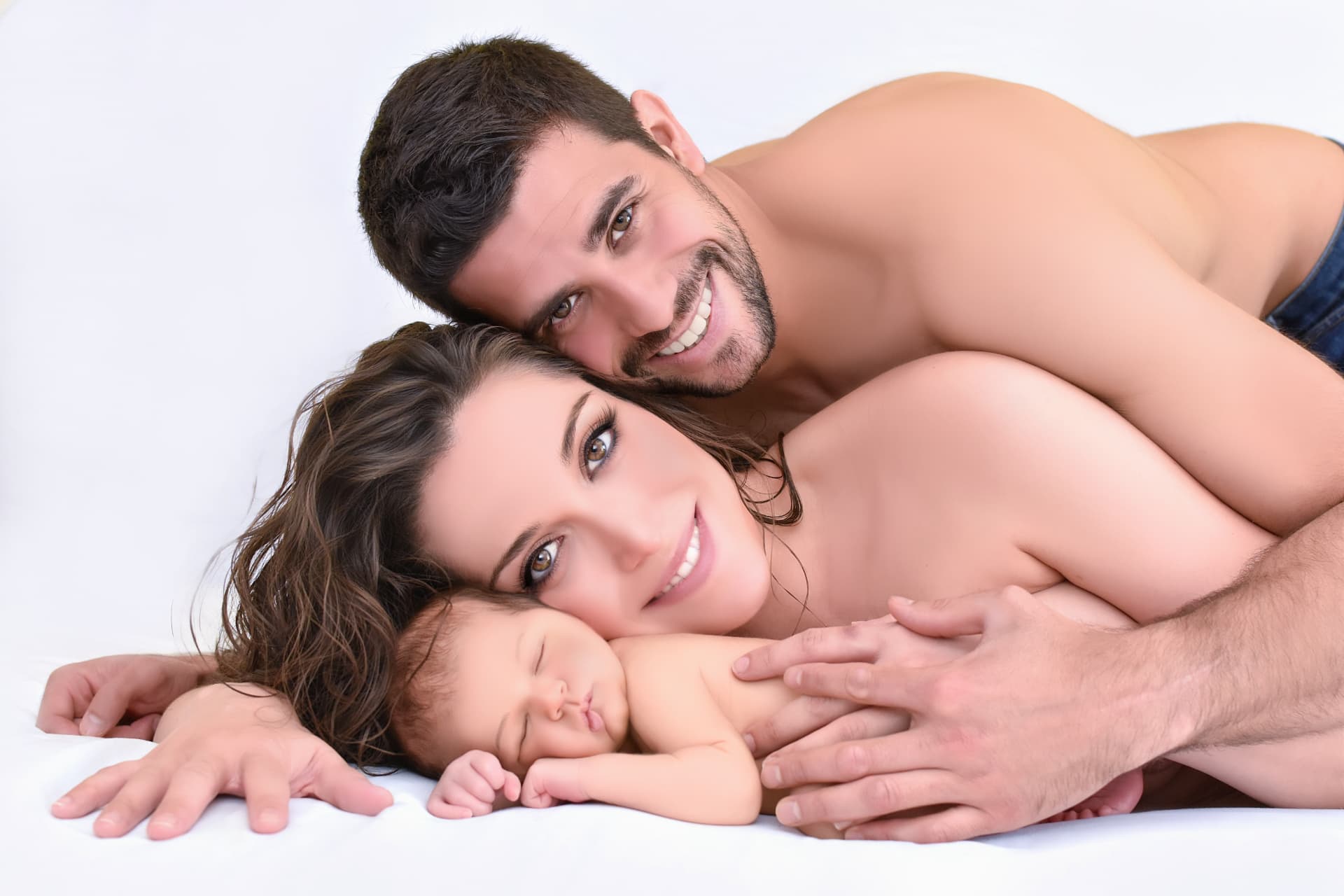 Padres abrazados junto a su bebé recién nacido en una sesión newborn en Madrid