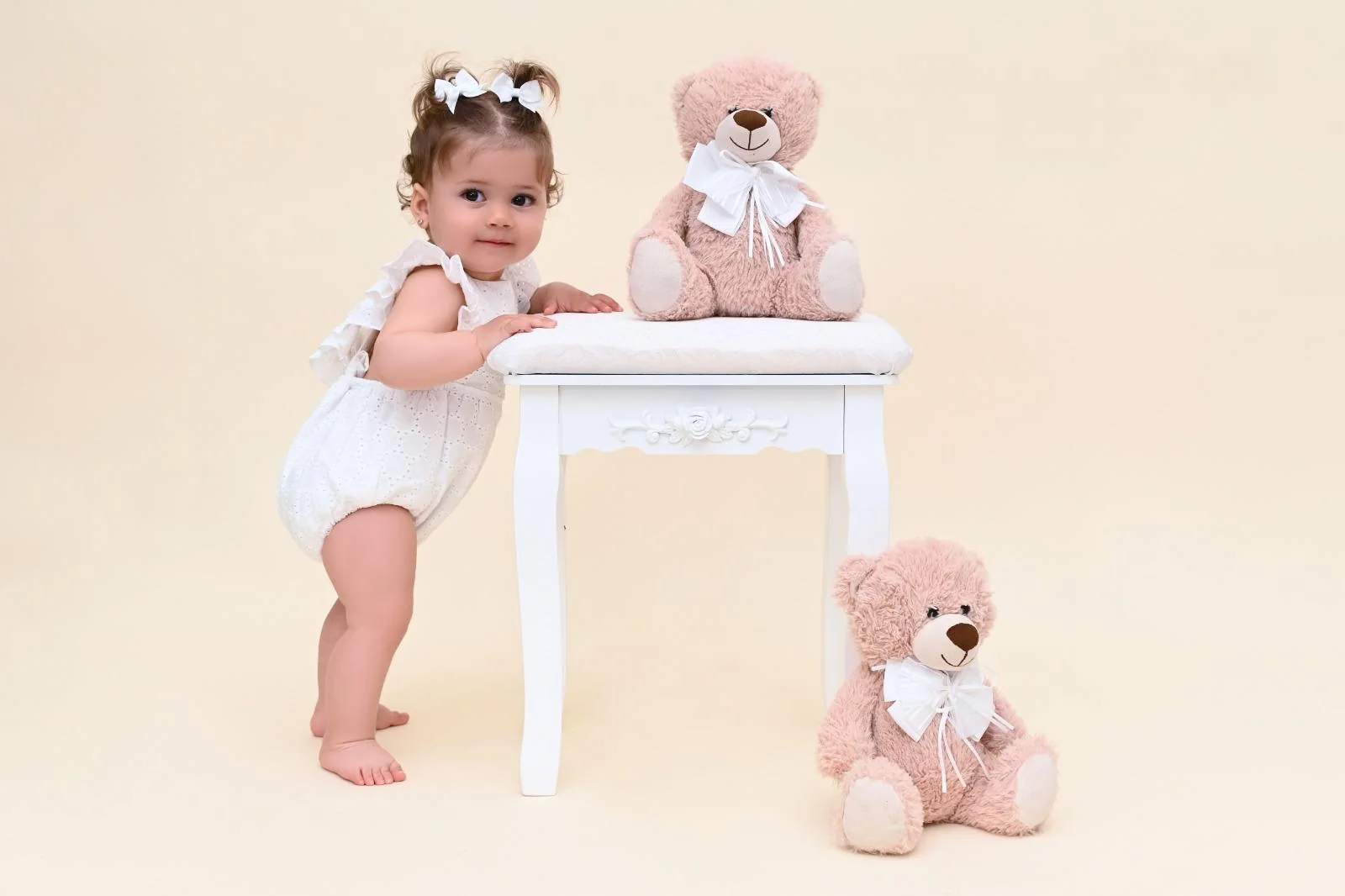 Niña de pie apoyada en un taburete blanco con ositos de peluche