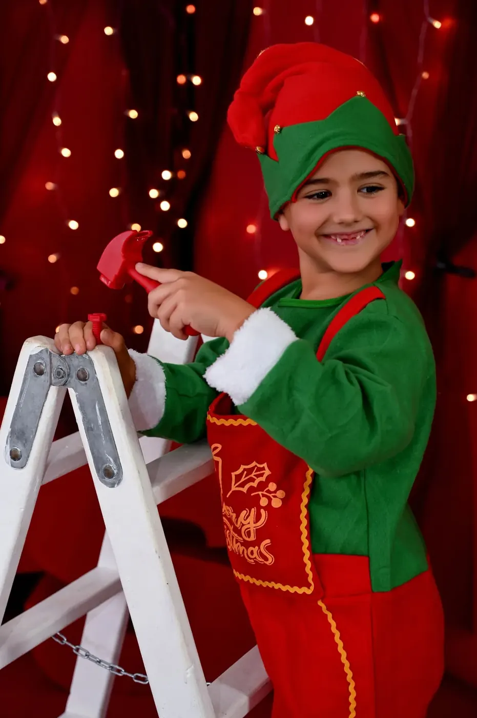 Niña vestida de elfa junto a una escalera en el decorado navideño